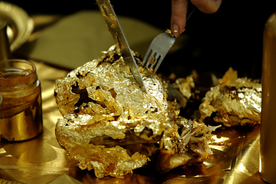 Artist and performer Frederique Lecerf carves a chicken covered with a thin sheet of gold as she prepares her performance meal for guests, a golden dinner with decadent 24 carat gold-covered dishes, in Paris, France,